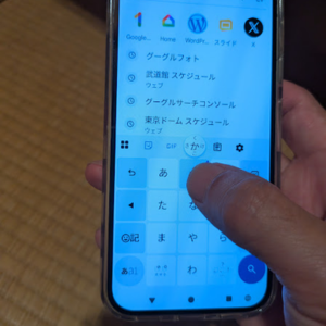 Google PixelでGboardの日本語12キーキーボードを表示し、指でフリック入力を操作している様子。Androidスマホのフリック入力方法を示す画像。